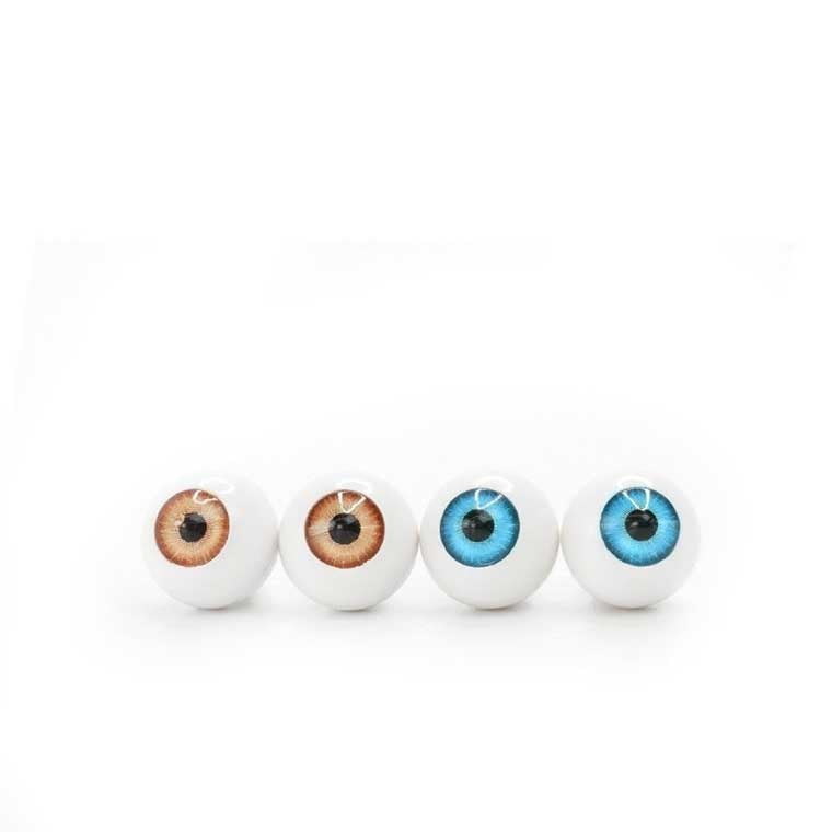 A pair of brown eye balls and a pair of blue eye balls sitting on a white surface.