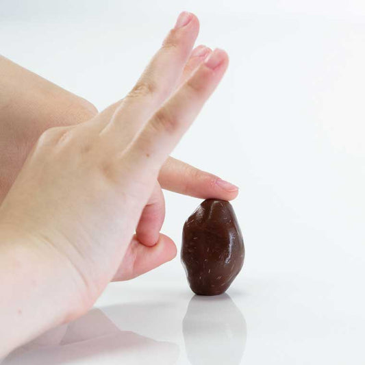 Hands flicking brown putty that is sculpted into the shape of a football.